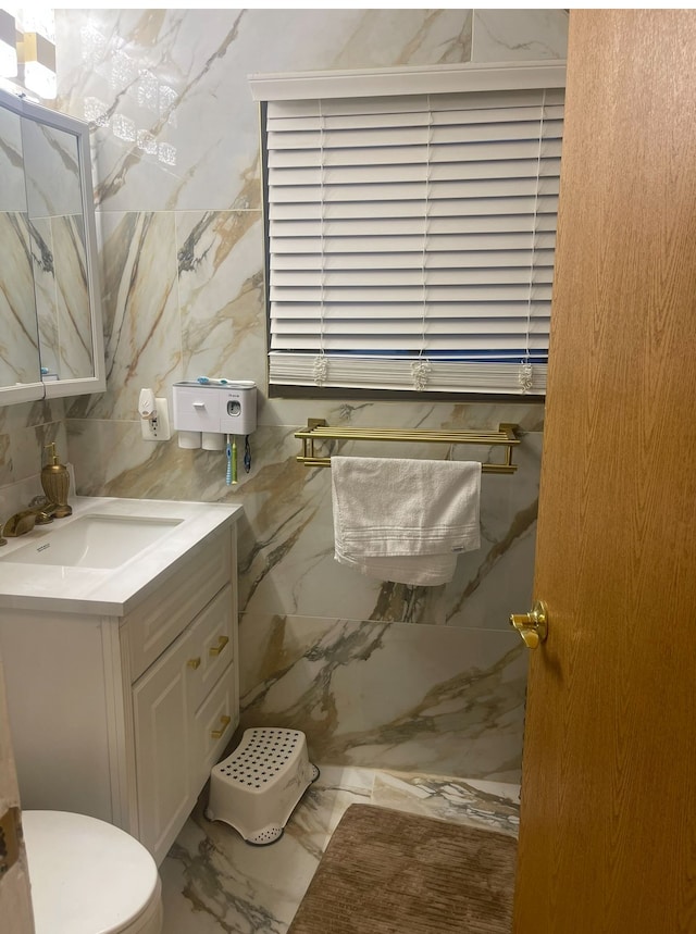 bathroom featuring vanity, toilet, and tile walls