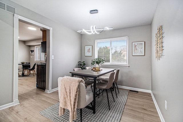 dining room featuring light wood-type flooring and an inviting chandelier