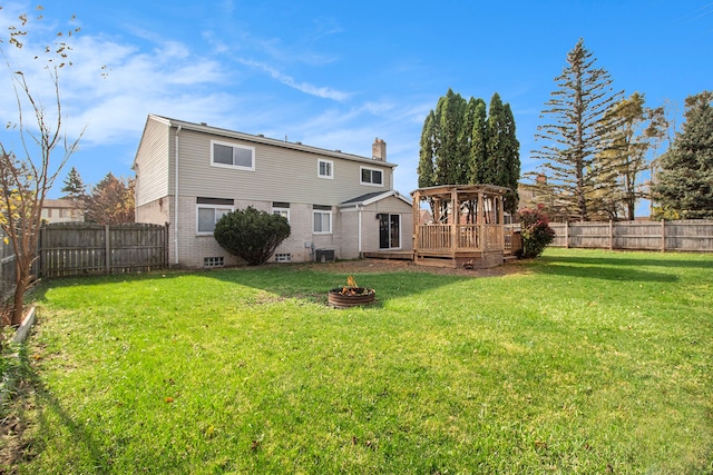 back of house featuring a lawn, central air condition unit, an outdoor fire pit, and a wooden deck