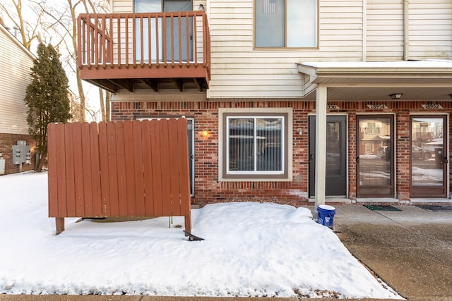 snow covered property entrance featuring a balcony