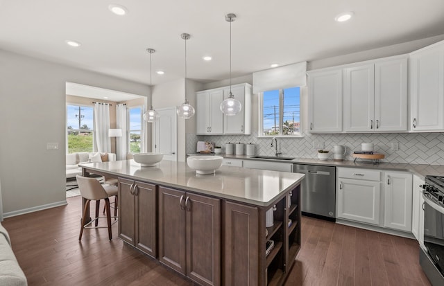 kitchen with a center island, sink, hanging light fixtures, stainless steel dishwasher, and white cabinets