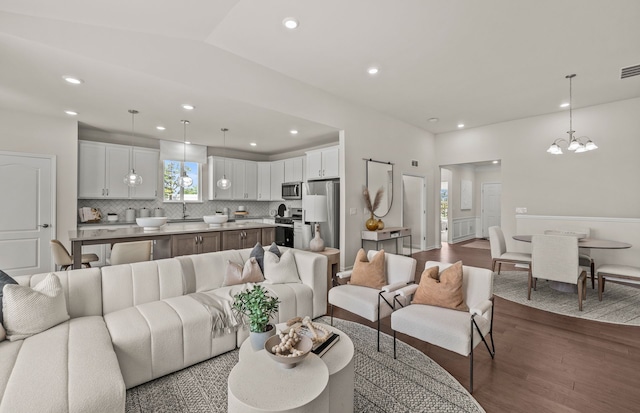 living room with a chandelier, hardwood / wood-style floors, and lofted ceiling