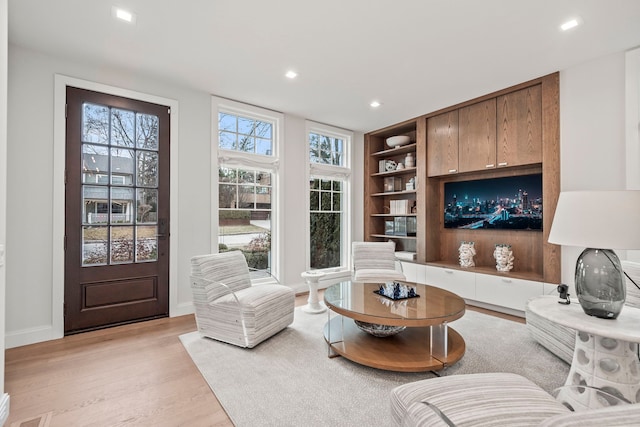 living room with built in shelves and light hardwood / wood-style flooring