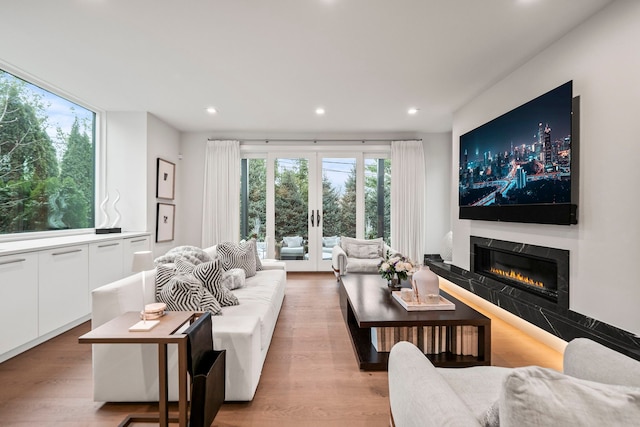 living room featuring light wood-type flooring, a fireplace, and french doors