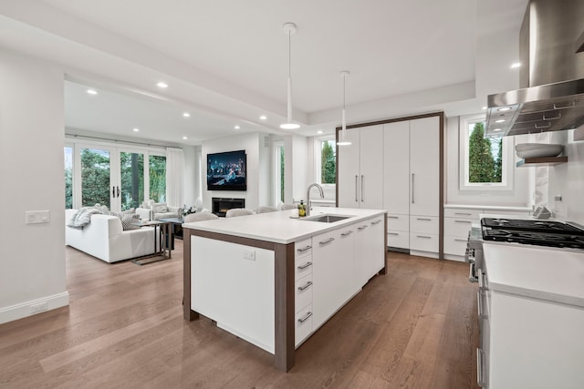 kitchen featuring sink, an island with sink, a wealth of natural light, decorative light fixtures, and white cabinetry