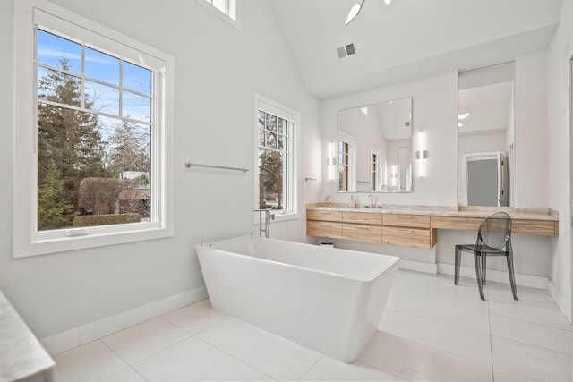 bathroom with tile patterned flooring, lofted ceiling, a wealth of natural light, and a bathing tub