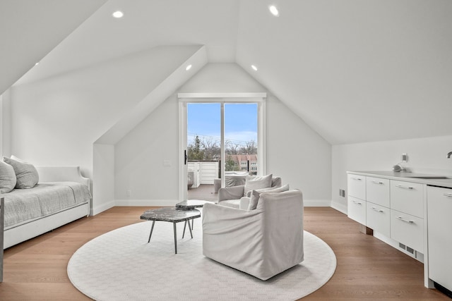 living room with light hardwood / wood-style floors, lofted ceiling, and sink