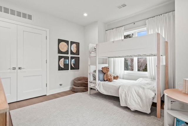 bedroom featuring a closet, hardwood / wood-style flooring, and multiple windows