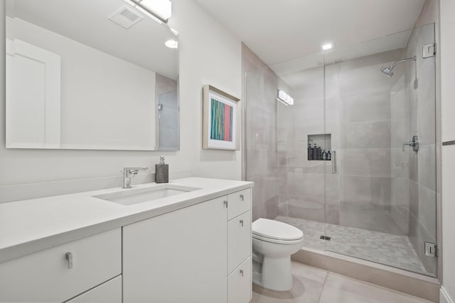 bathroom featuring tile patterned floors, a shower with door, vanity, and toilet