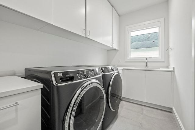 clothes washing area featuring washer and dryer, sink, and cabinets