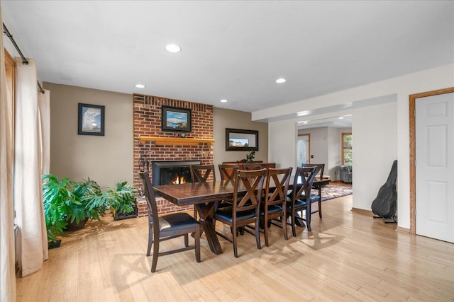 dining room with a brick fireplace and light hardwood / wood-style floors