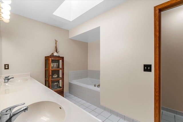 bathroom featuring a skylight, tile patterned flooring, tiled bath, and vanity