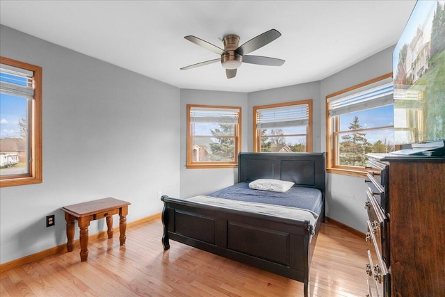 bedroom with multiple windows, ceiling fan, and light hardwood / wood-style flooring