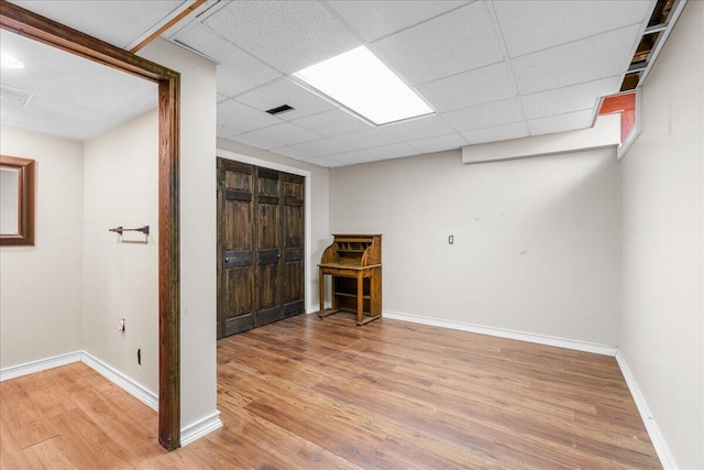 basement featuring a paneled ceiling and wood-type flooring