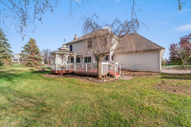 rear view of property featuring a lawn, a wooden deck, and a gazebo