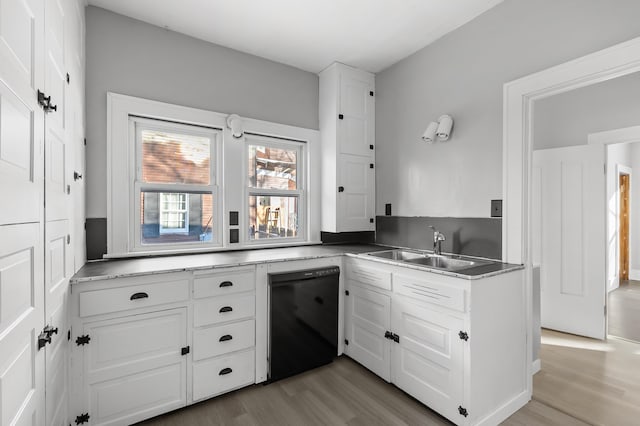 kitchen with light hardwood / wood-style floors, black dishwasher, sink, and white cabinets