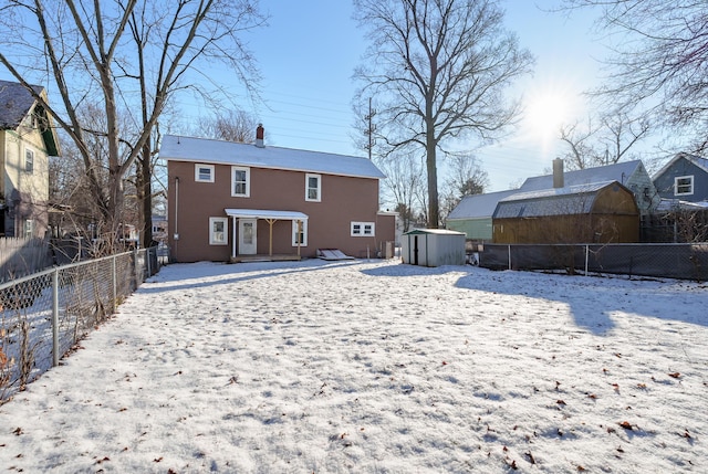 snow covered house featuring a storage shed