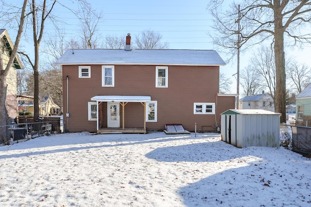 snow covered back of property with a shed