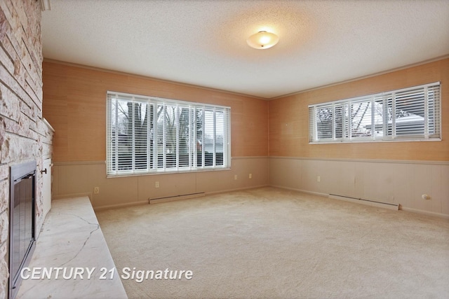 unfurnished living room featuring a fireplace, carpet floors, a baseboard radiator, and a textured ceiling