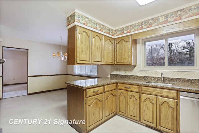 kitchen with stainless steel dishwasher, a notable chandelier, kitchen peninsula, and sink