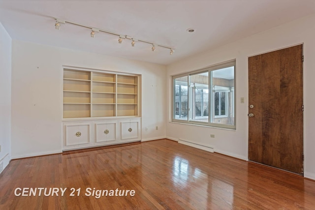 unfurnished living room featuring hardwood / wood-style floors, built in features, and baseboard heating