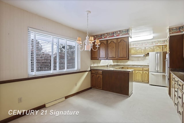 kitchen featuring stainless steel fridge, a baseboard heating unit, sink, decorative light fixtures, and an inviting chandelier