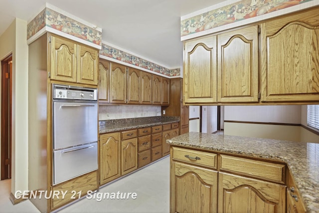 kitchen with multiple ovens and dark stone countertops