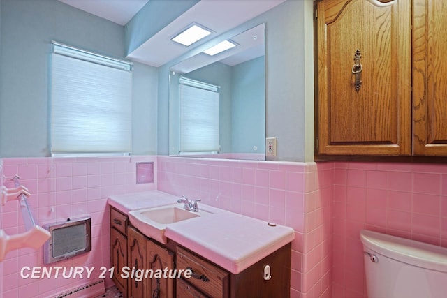 bathroom with vanity, a healthy amount of sunlight, tile walls, and a baseboard heating unit