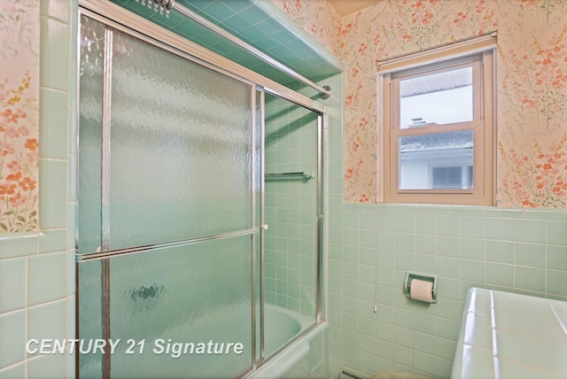 bathroom with bath / shower combo with glass door and tile walls