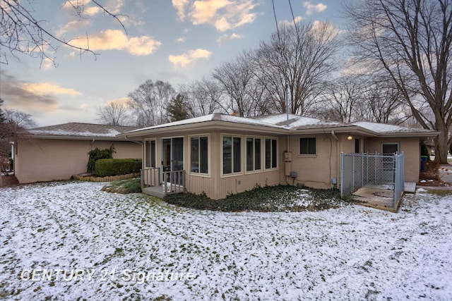 snow covered property featuring a sunroom