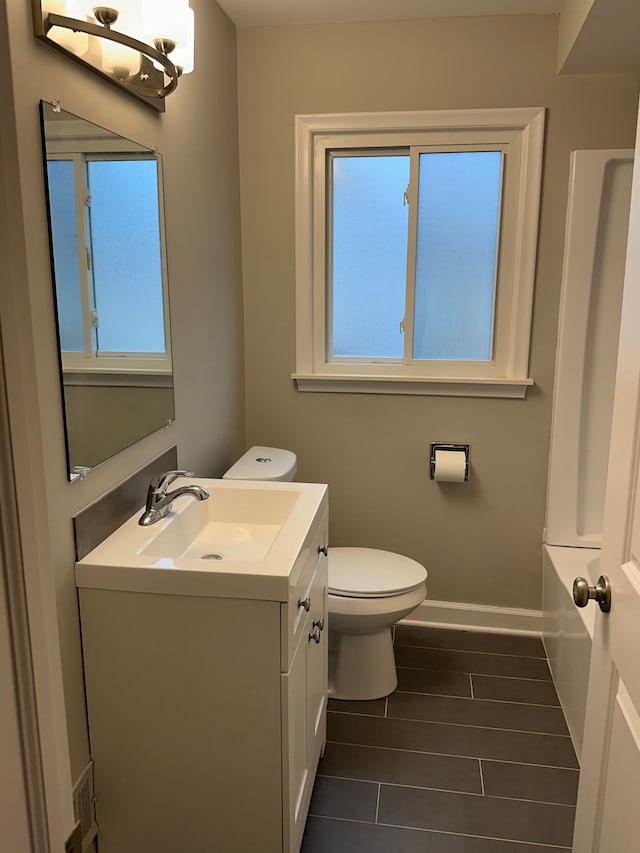 full bathroom featuring a wealth of natural light, vanity, toilet, and baseboards