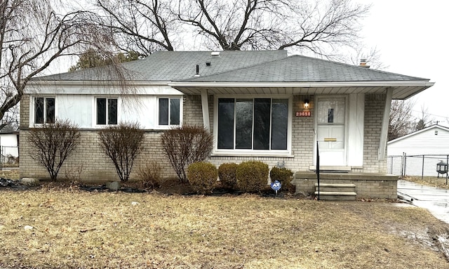 view of front of house with brick siding, a shingled roof, and an outdoor structure