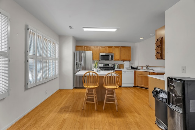 kitchen featuring a breakfast bar, a center island, sink, appliances with stainless steel finishes, and light hardwood / wood-style floors