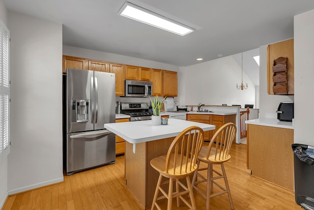 kitchen with appliances with stainless steel finishes, a kitchen breakfast bar, sink, pendant lighting, and a chandelier