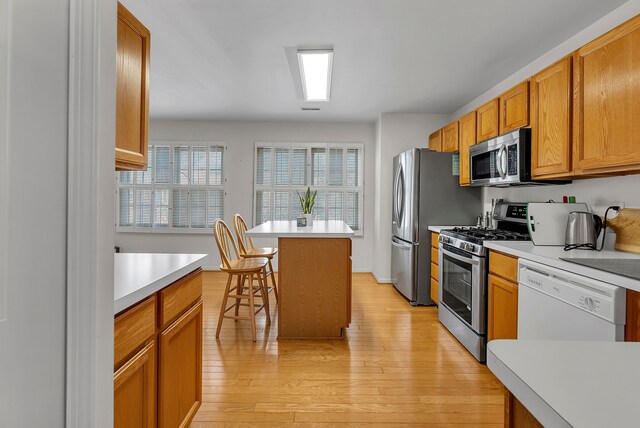 kitchen featuring a kitchen island, a kitchen bar, light hardwood / wood-style floors, and stainless steel appliances