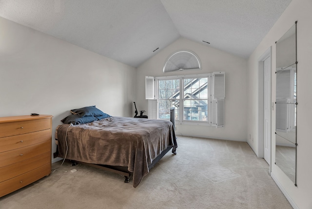 bedroom featuring a textured ceiling, light colored carpet, and lofted ceiling