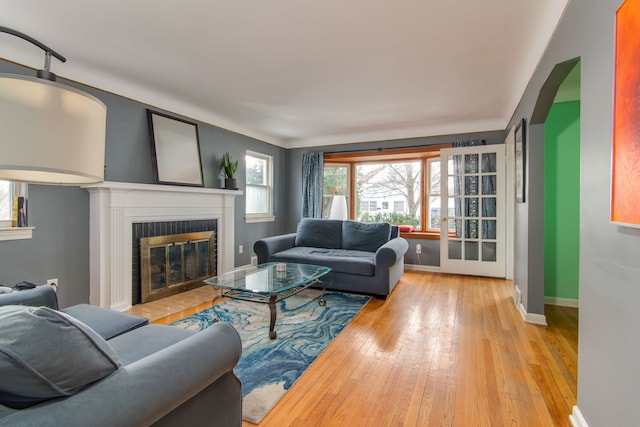 living room with a brick fireplace, a wealth of natural light, and light hardwood / wood-style flooring