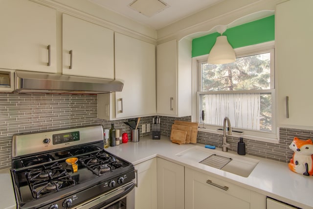 kitchen featuring sink, gas range, white cabinets, and backsplash