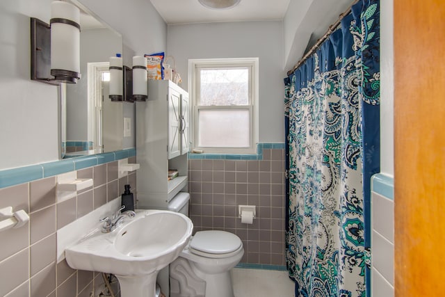 bathroom with sink, tile walls, a shower with shower curtain, and toilet