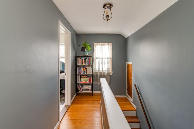 hallway with light hardwood / wood-style flooring and vaulted ceiling