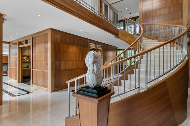 staircase with a towering ceiling and wood walls