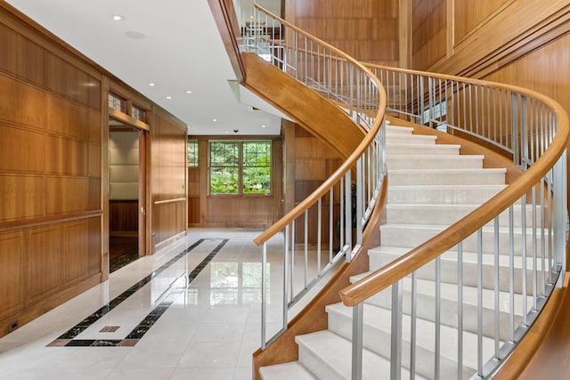 stairway featuring tile patterned floors and wooden walls