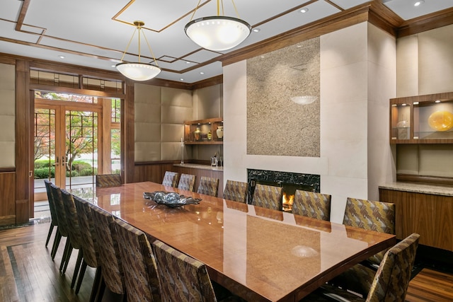 dining room featuring dark hardwood / wood-style flooring, a premium fireplace, french doors, and ornamental molding