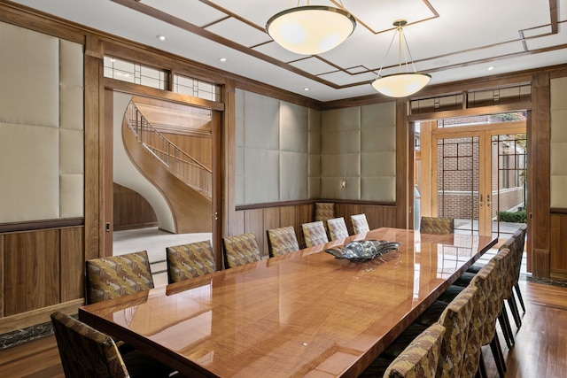 dining room with hardwood / wood-style flooring, wooden walls, and french doors