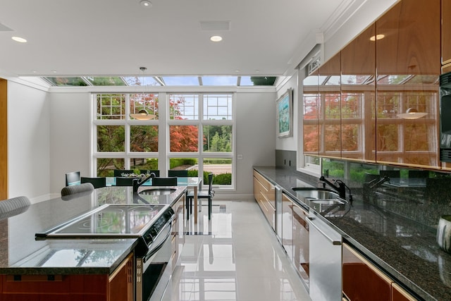 kitchen with a kitchen breakfast bar, sink, stainless steel appliances, and dark stone countertops