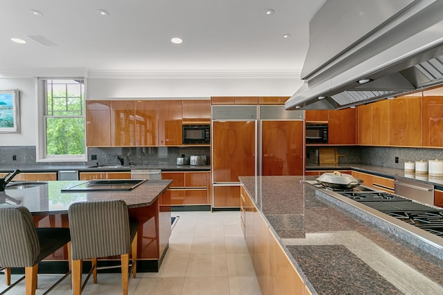 kitchen featuring sink, island exhaust hood, built in appliances, a spacious island, and a breakfast bar