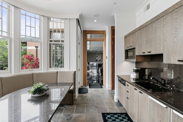 kitchen with dark stone counters, black microwave, crown molding, sink, and light brown cabinets