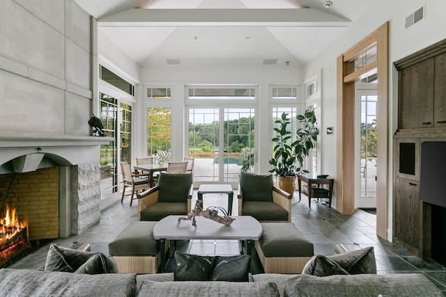 sunroom / solarium with lofted ceiling with beams, a healthy amount of sunlight, and a fireplace