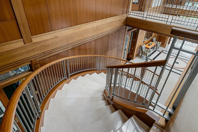 stairway featuring wooden walls and a towering ceiling