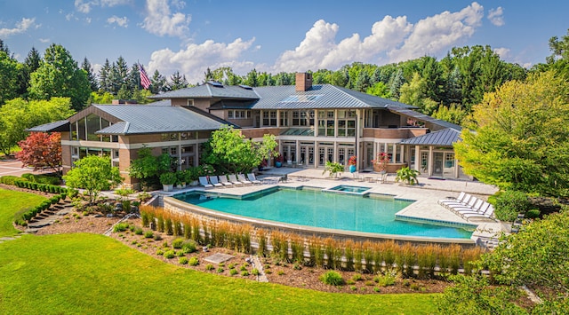 back of property featuring a lawn, a patio area, and a pool with hot tub